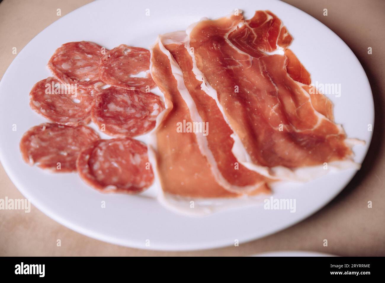 A white plate with assorted cured meats including salami and prosciutto Stock Photo