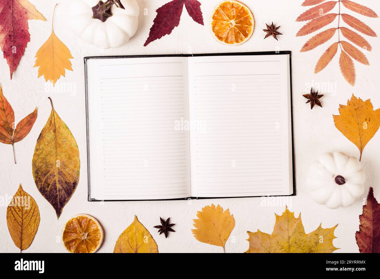 Notepad on white table with autumn leaves pattern Stock Photo