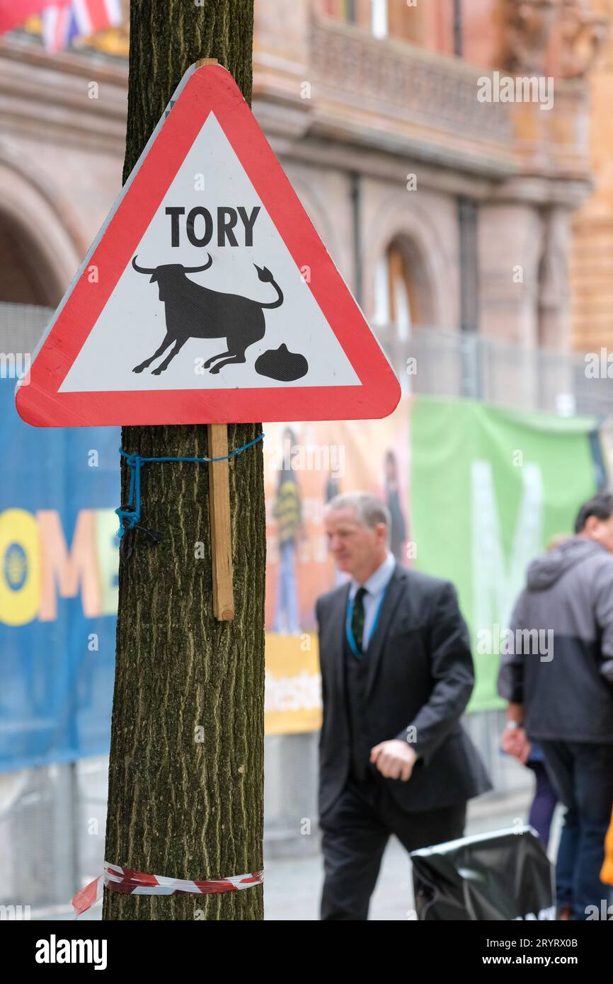 Manchester, UK - Monday 2nd October 2023 – A delegate walks past a 'Tory bullshit' sign outside the Conservative Party Conference - Photo Steven May / Alamy Live News Stock Photo