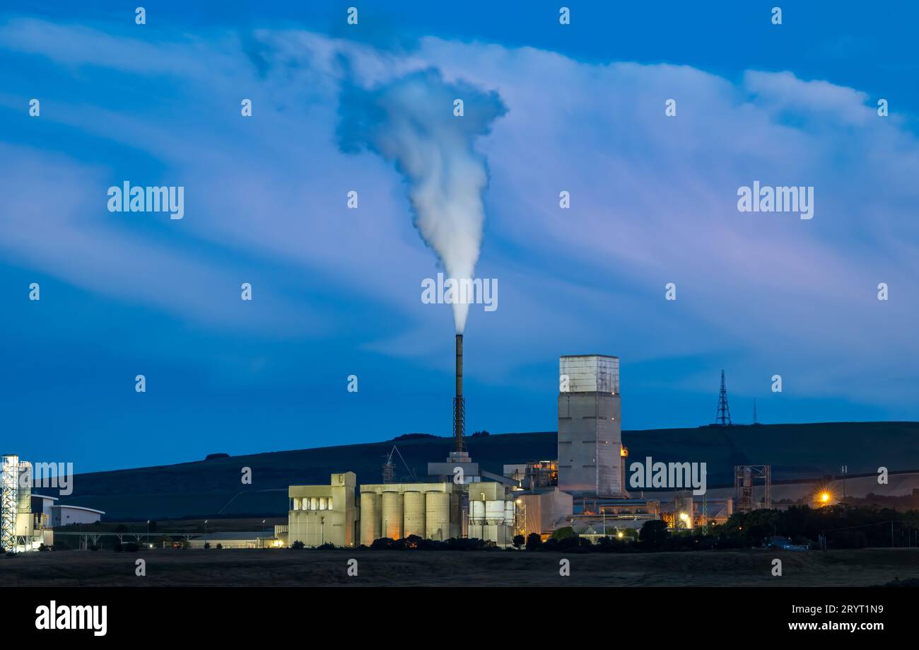 Dunbar cement works lit up at dusk with industrial steam tower, East
