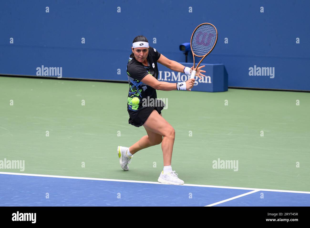 A female athlete Ons Jabeur in a tennis court, sporting a racquet and