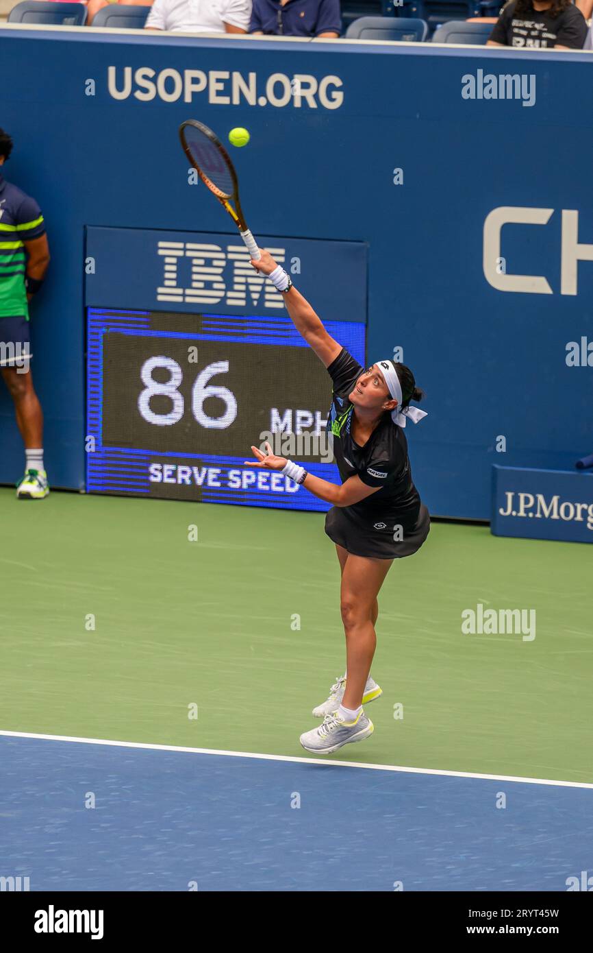 A female athlete Ons Jabeur in a tennis court, sporting a racquet and