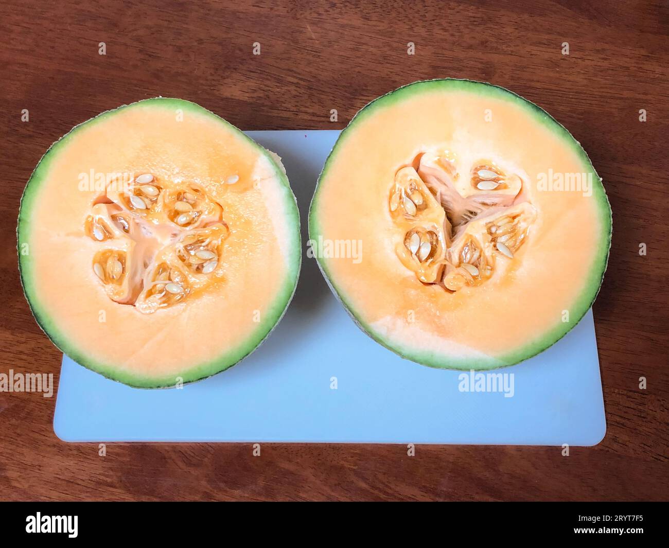 Freshly cut Rockmelon cut into half on a white cutting board in the