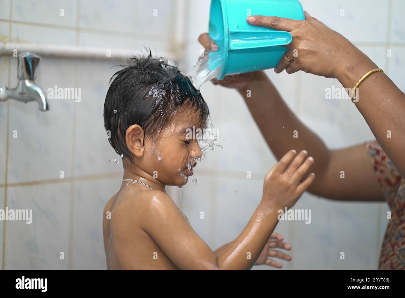 A 2yearold Indian baby boy enjoying a bath in a green tub Stock Photo