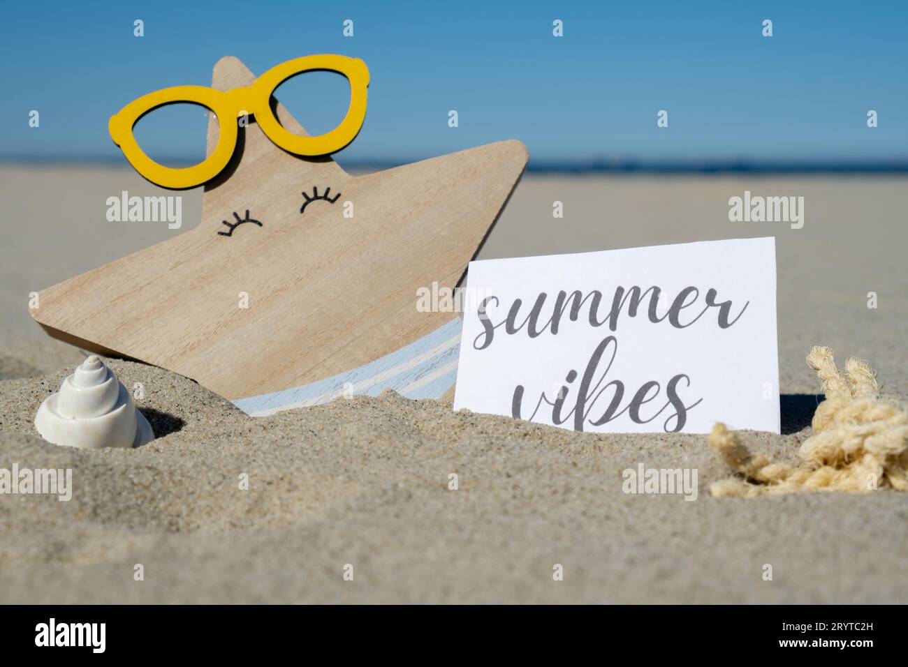 SUMMER VIBES text on paper greeting card on background of funny starfish in glasses summer vacation decor. Sandy beach sun coast Stock Photo