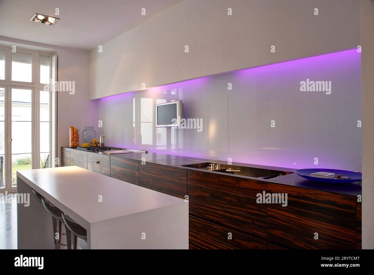Galley kitchen white with purple lighting and island. End House