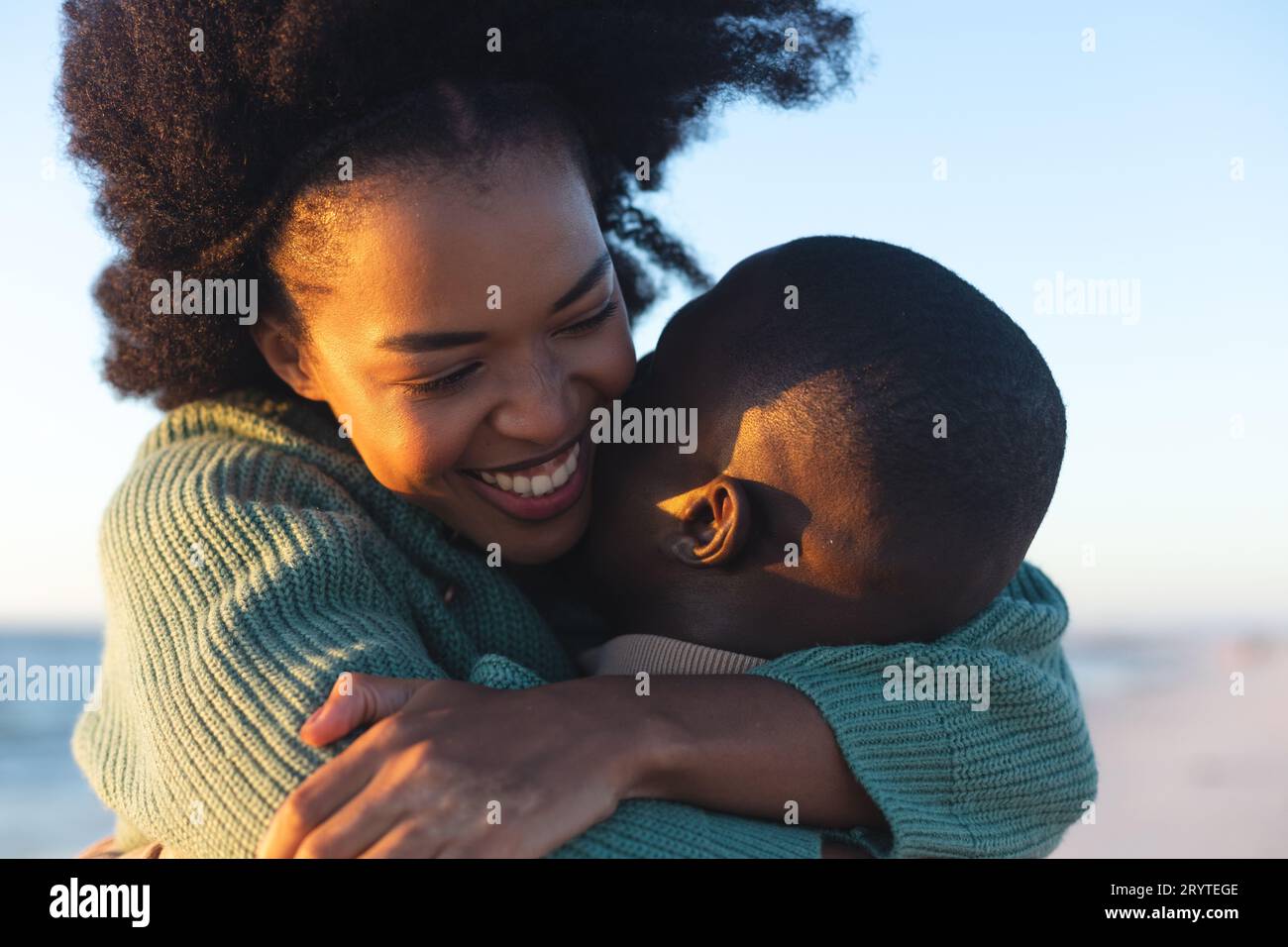 Happy african american couple embracing and smiling on sunny beach ...