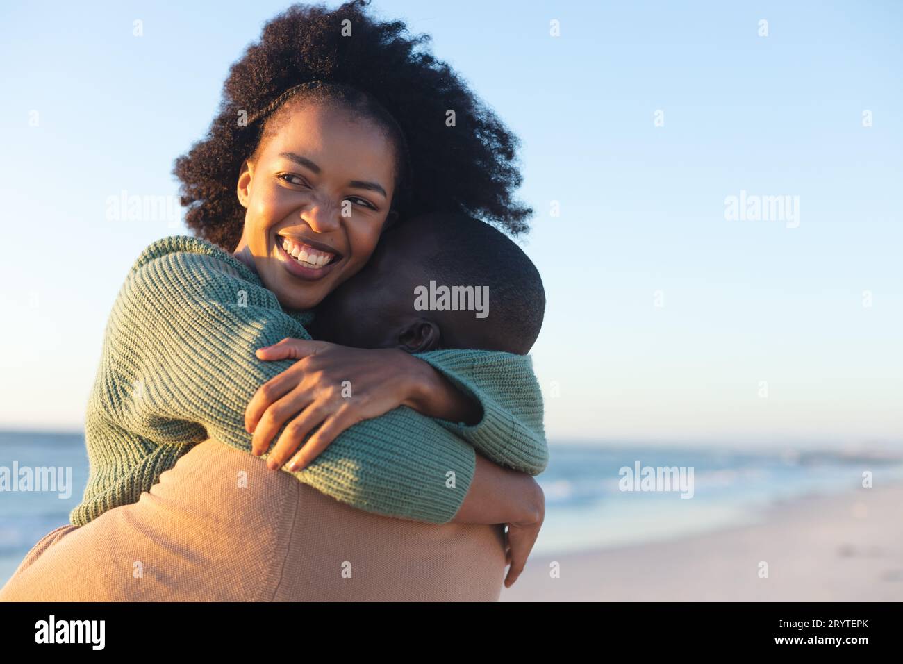 Happy african american couple embracing and smiling on sunny beach ...