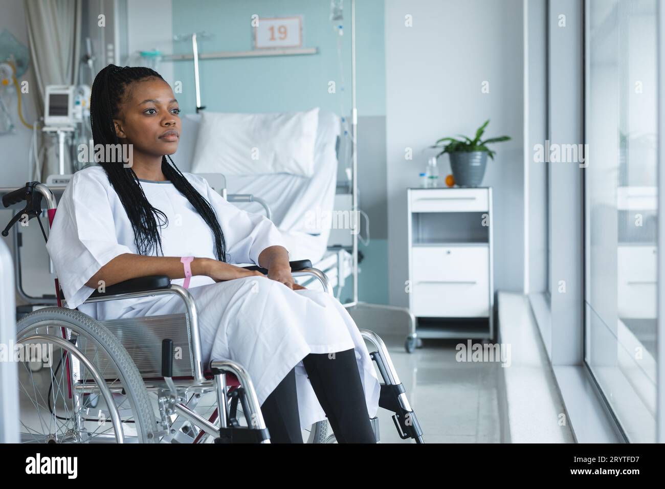 African american female patient wearing hospital gown, sitting in