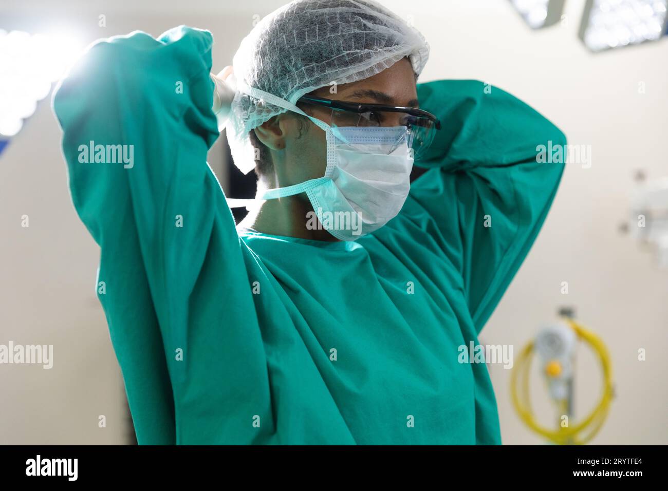 African american female surgeon wearing surgical gown and face mask in operating theatre Stock Photo