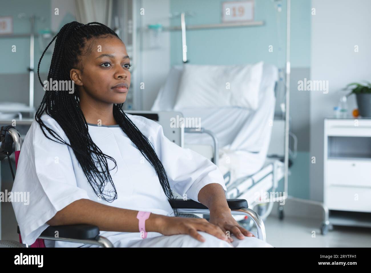 African american female patient wearing hospital gown, sitting in