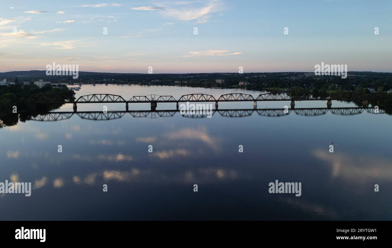 A long bridge spanning across a body of water, with its reflection visible in the calm and still water Stock Photo