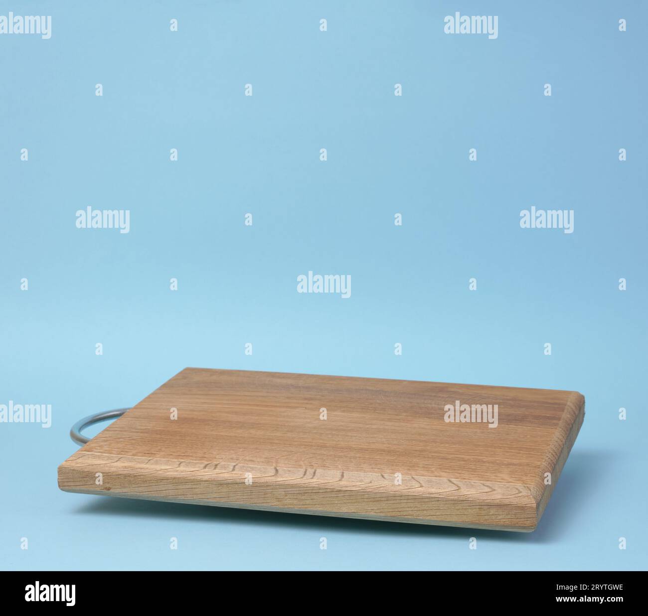 Wooden empty cutting board at an angle on a blue background, kitchen