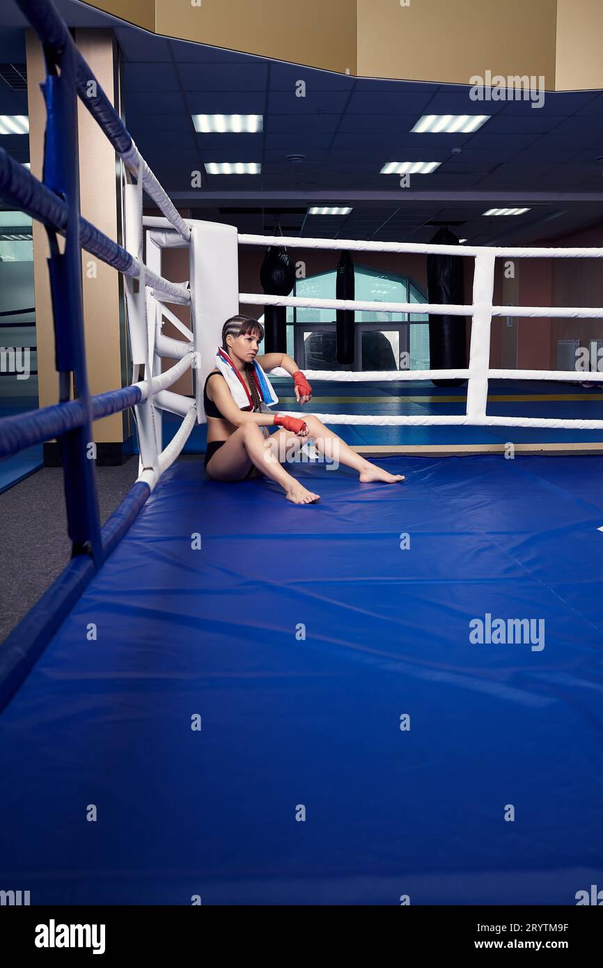 Female fighter with boxing taping bandage on her hands sits in a boxing ...