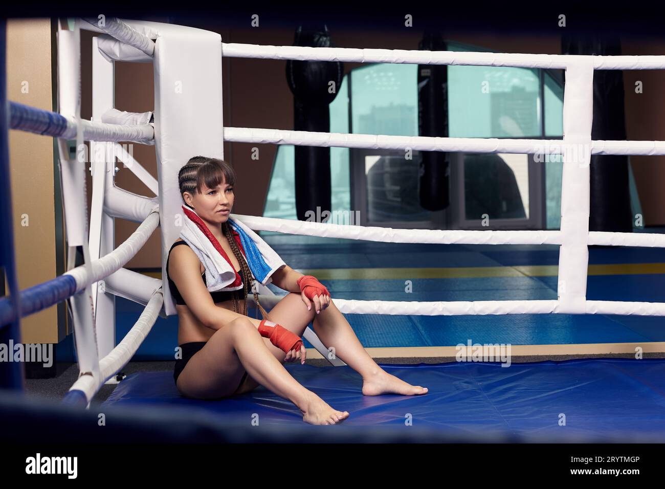 Female fighter with boxing taping bandage on her hands sits in a boxing ...