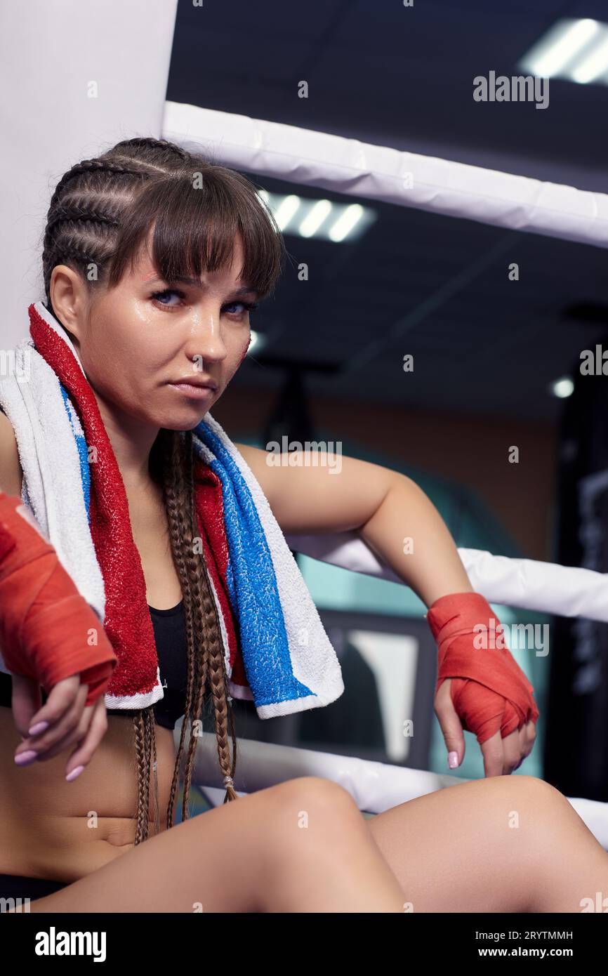 Female fighter with boxing taping bandage on her hands sits in a boxing ...