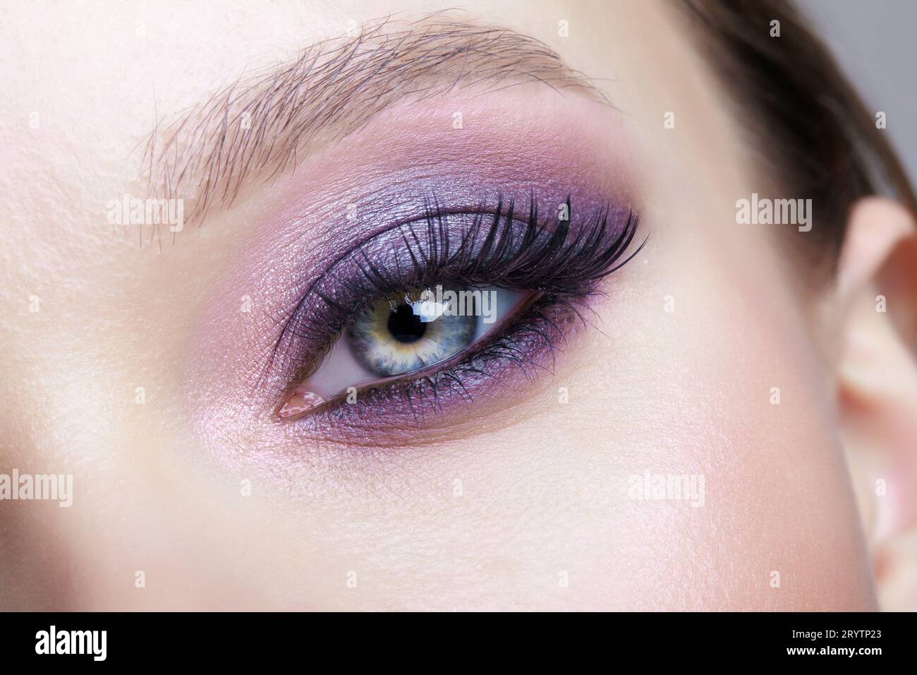 Closeup macro shot of human female eye. Woman with lilac beauty eyes makeup. Stock Photo
