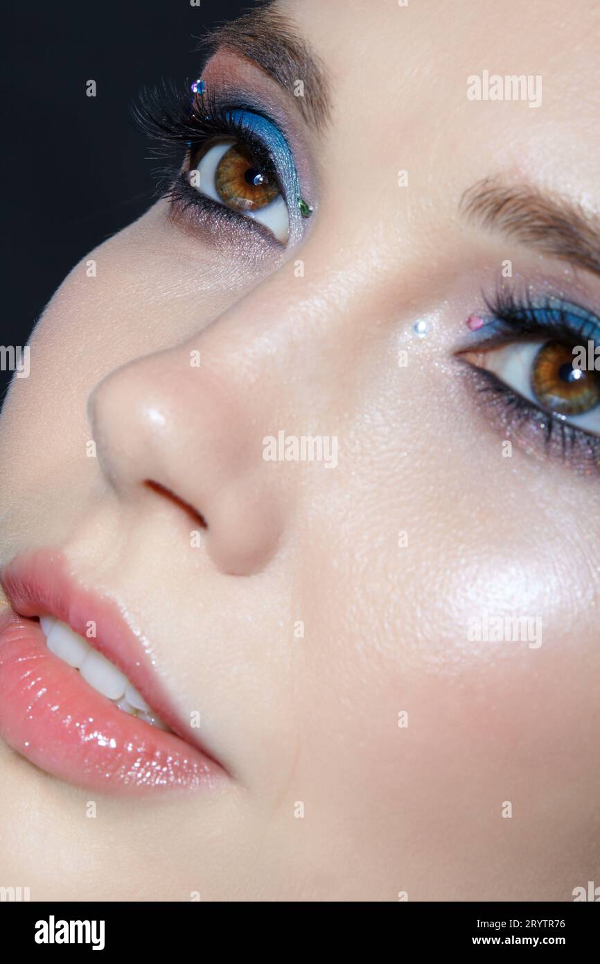 Closeup shot of human woman face. Female with face and eyes beauty makeup with blue eye shadow make up and rhinestones Stock Photo