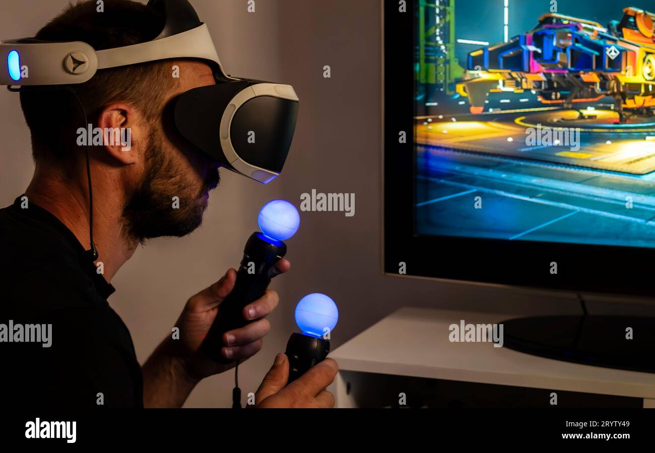 Man wearing VR headset with controllers playing a game Stock Photo