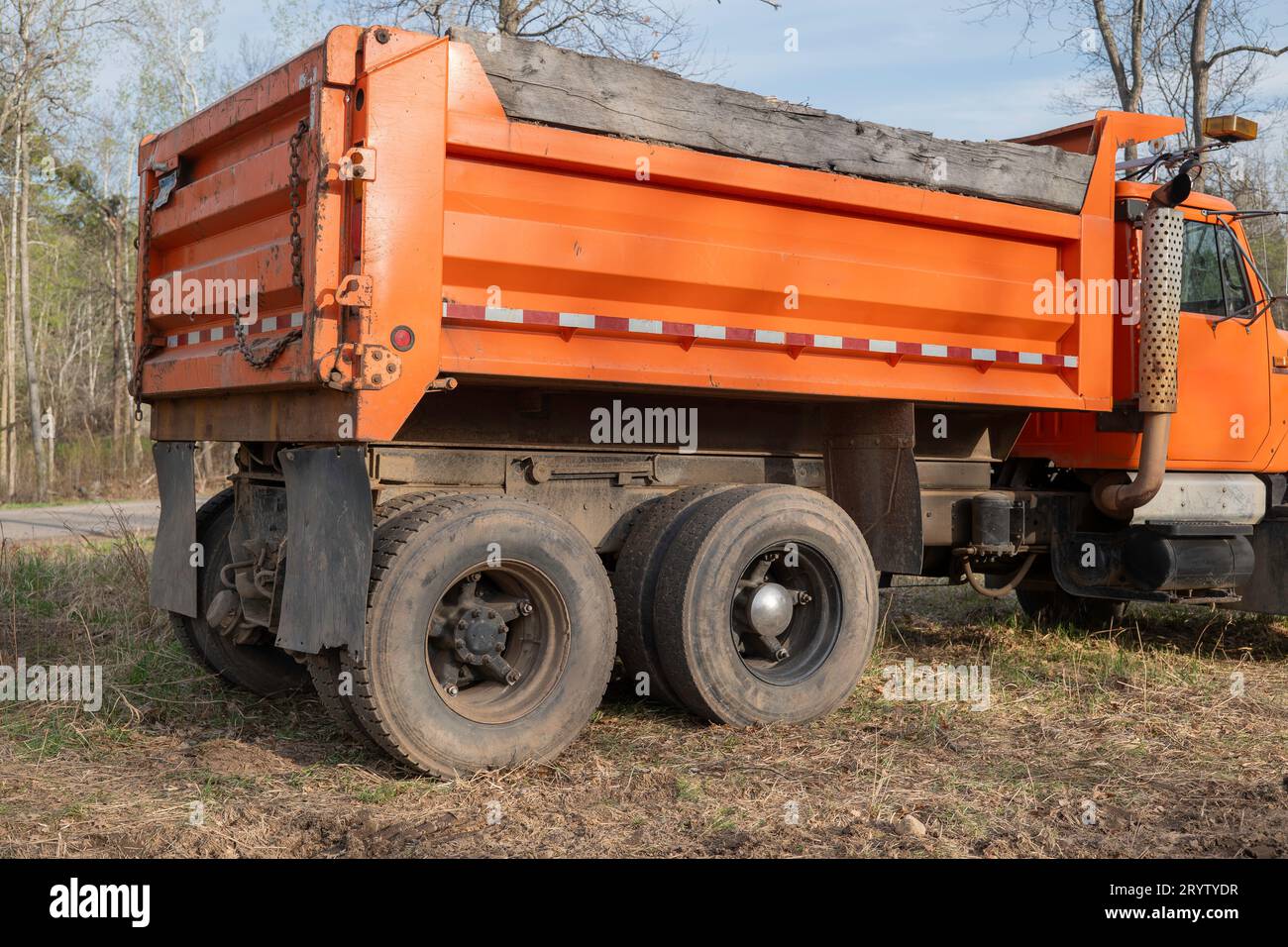 An older well-used orange gravel or dump truck box, from back corner view. Stock Photo