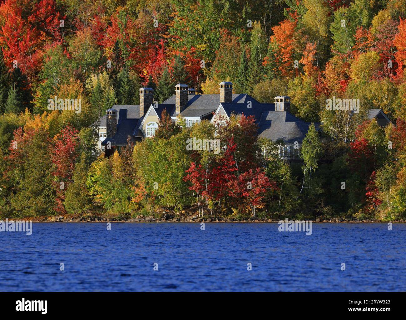 House on the border of the lake surrounded by autumn color in Mont Tremblant, Quebec, Canada Stock Photo