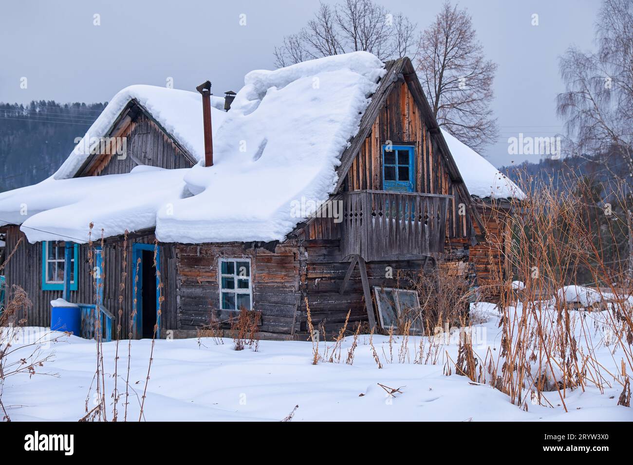 Old abandoned wooden house. The roof is covered with a thick layer of ...