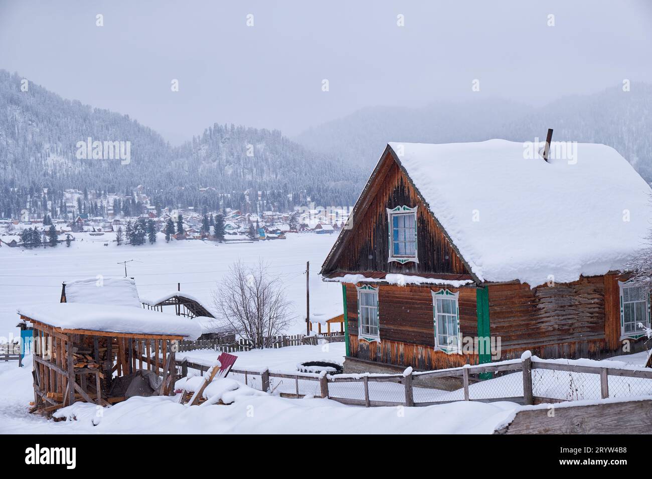 Old wooden house. The roof is covered with a thick layer of snow. Altai village Artybash in winter season. Stock Photo