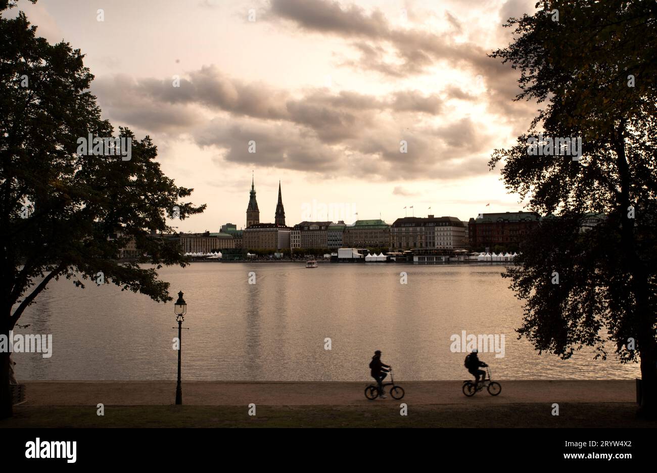 HAMBURG, Germany - 30 September 2023 - Cyclists cycle along the Small Alster Lake in Hamburg at dusk. Picture: Giordano Stolley Stock Photo