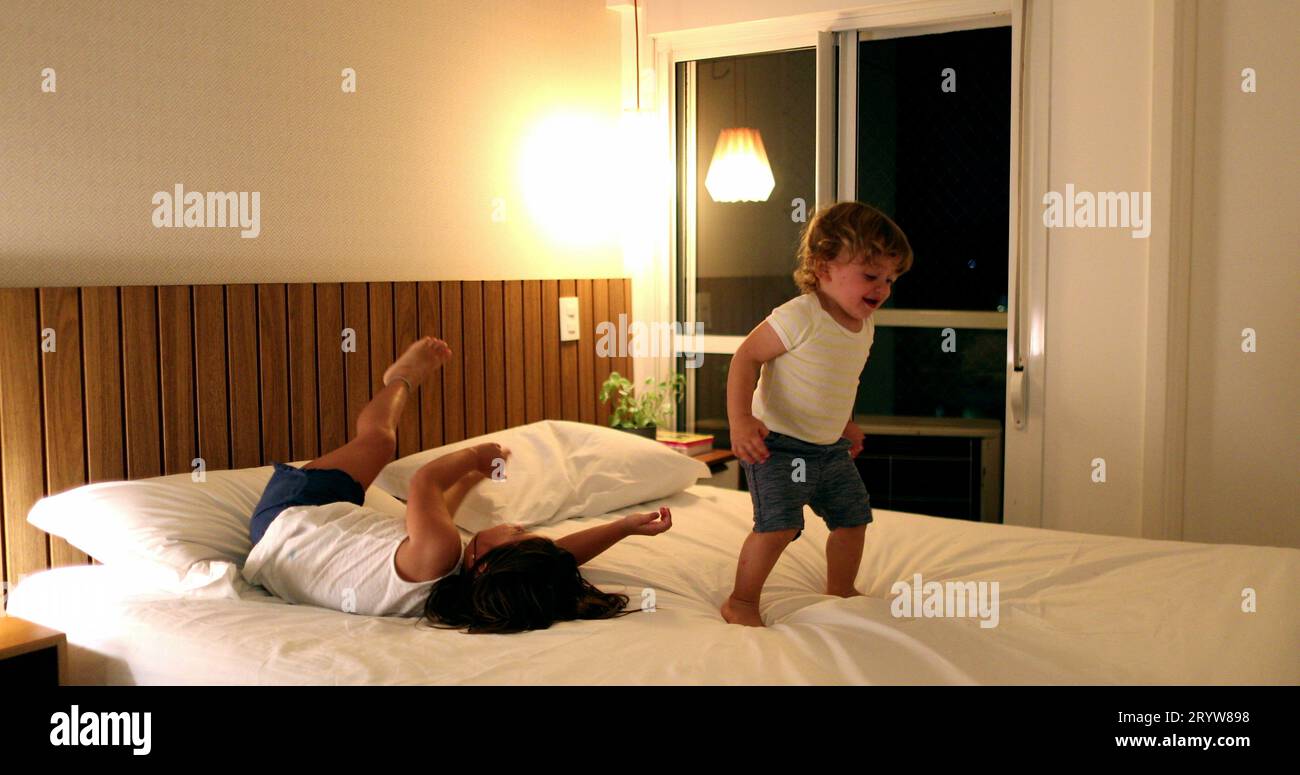 Fun active children diving into bed, little girl boy toddler bouncing