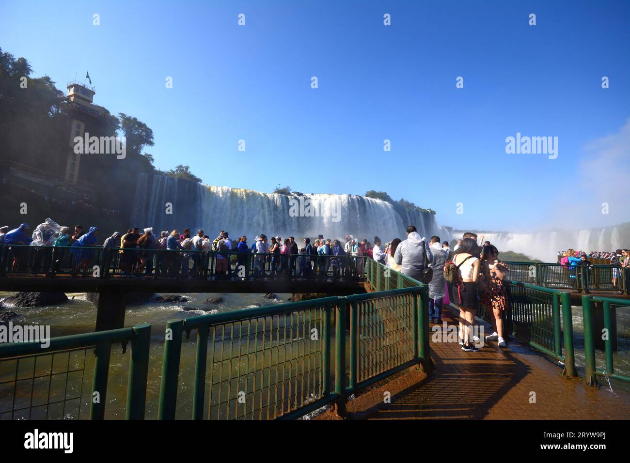Tourists at Iguazu Falls, one of the great natural wonders of the world, on the border of Brazil and Argentina with a panoramic elevator on the left Stock Photo