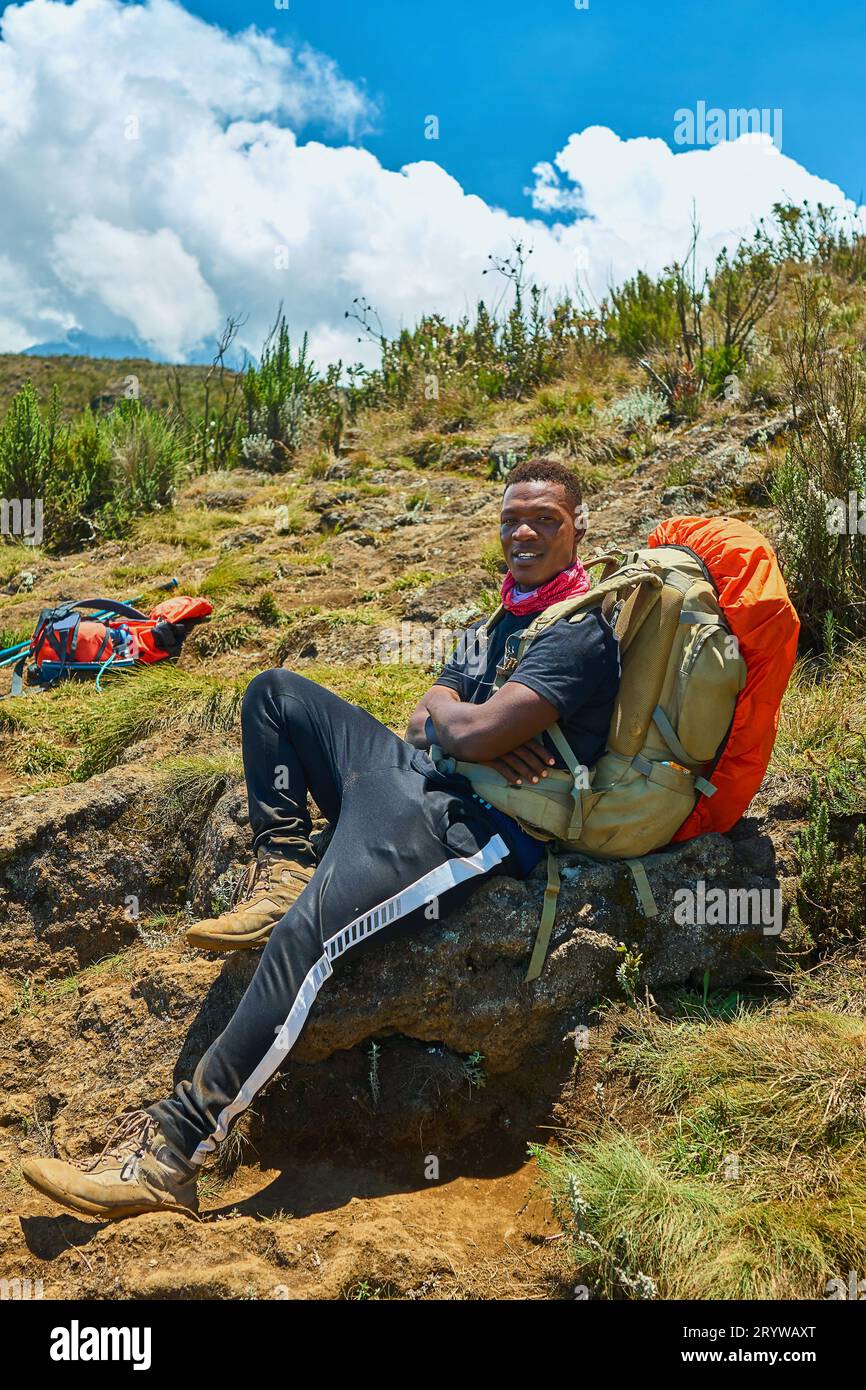a dark-skinned guy with a backpack is resting in the mountains Stock Photo