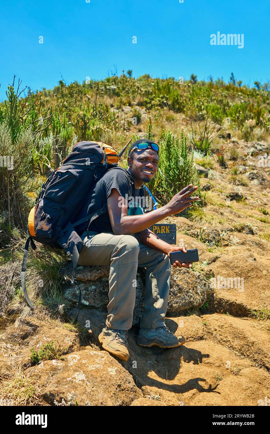 a dark-skinned guy with a backpack is resting in the mountains Stock Photo