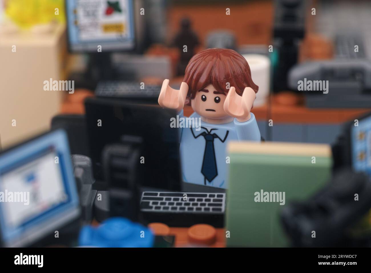 Tambov, Russian Federation - September 30, 2023 A frightened Lego businessman minifigure sitting behind a computer in an office. Close up. Stock Photo