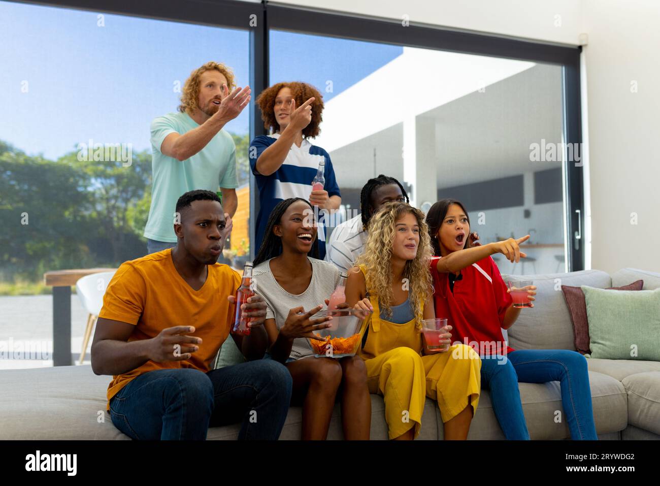 Group of focused diverse friends sitting on sofa, watching sport of tv Stock Photo