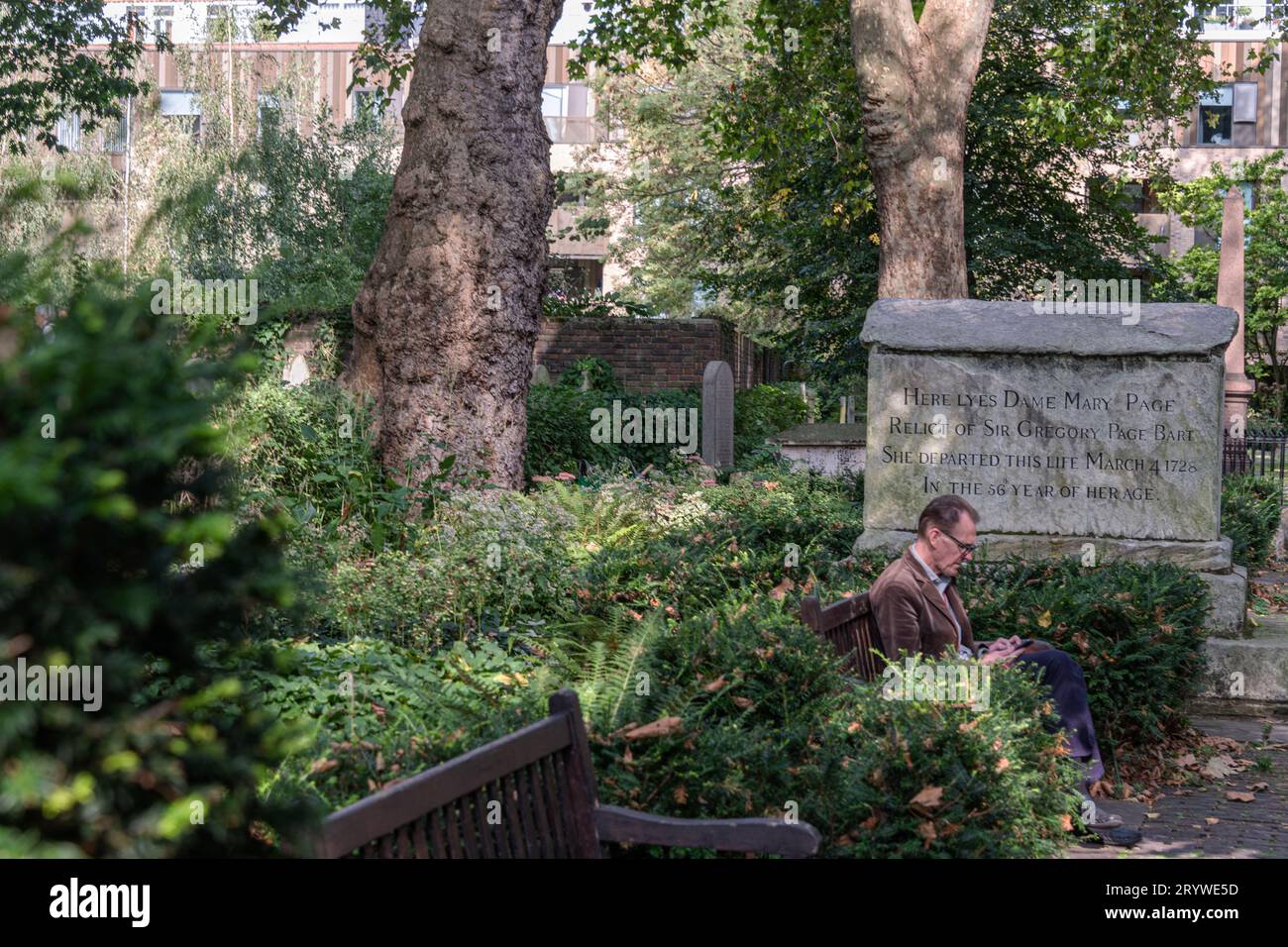 A man rests in Bunhill Fields Burial Ground, London EC1. Stock Photo