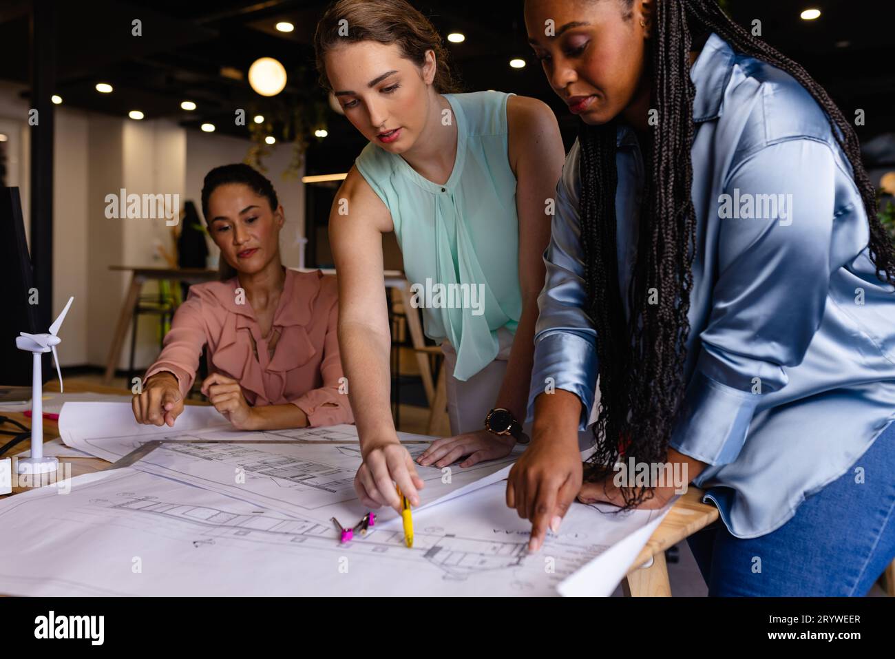 Blueprint Discussion Diverse female architects in discussion using blueprints in casual ...