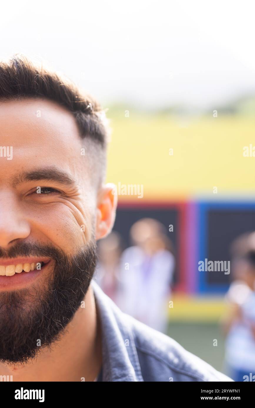 Vertical half face portrait of smiling, bearded caucasian male school teacher outdoors, copy space Stock Photo