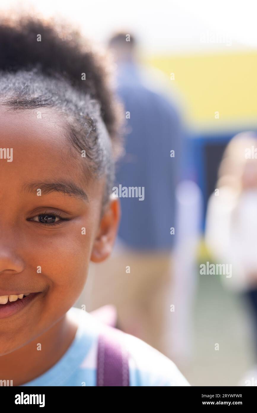 Vertical half face portrait of smiling african american elementary schoolgirl outdoors, copy space Stock Photo