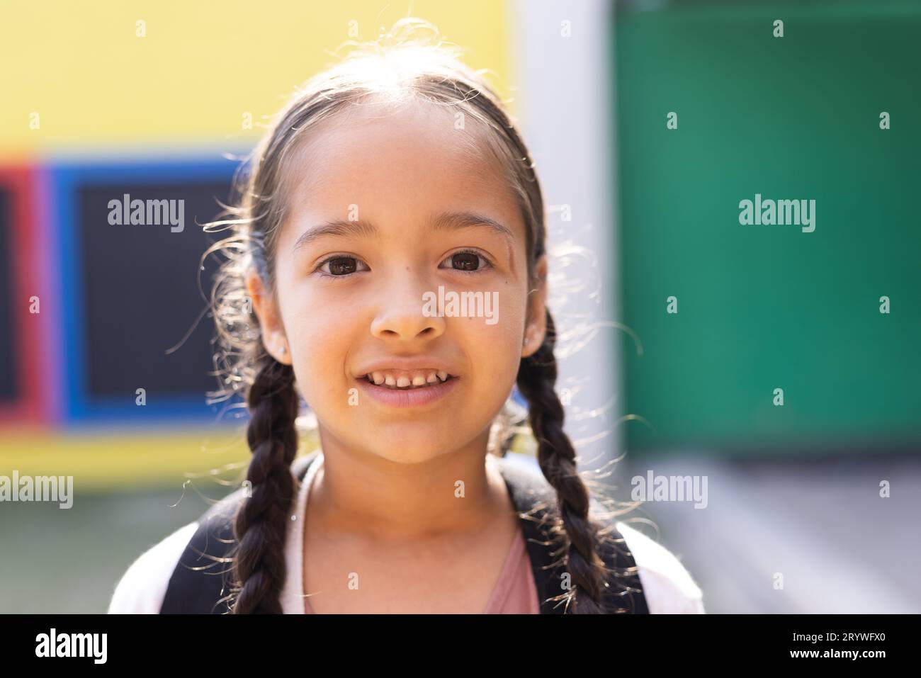 Portrait of smiling cauasian elementary schoolgirl in school playground ...