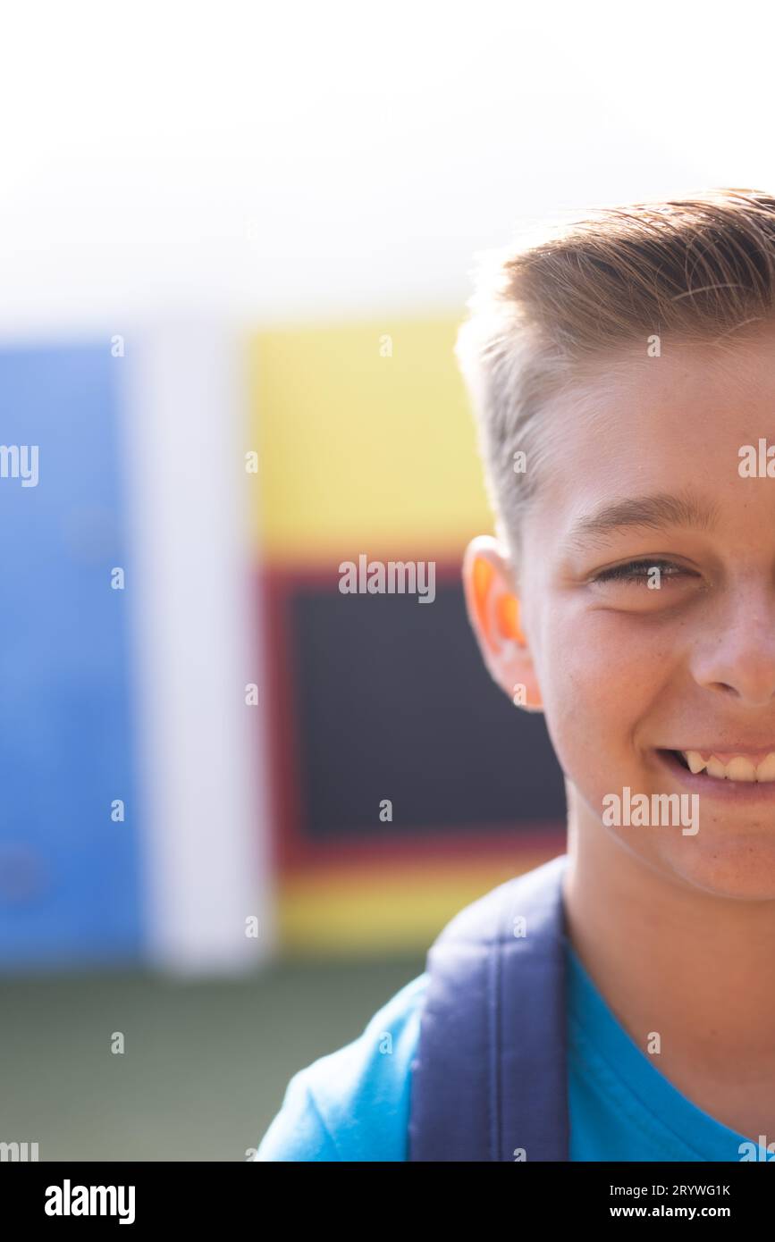 Vertical half face portrait of smiling caucasian elementary schoolboy in schoolyard, copy space Stock Photo