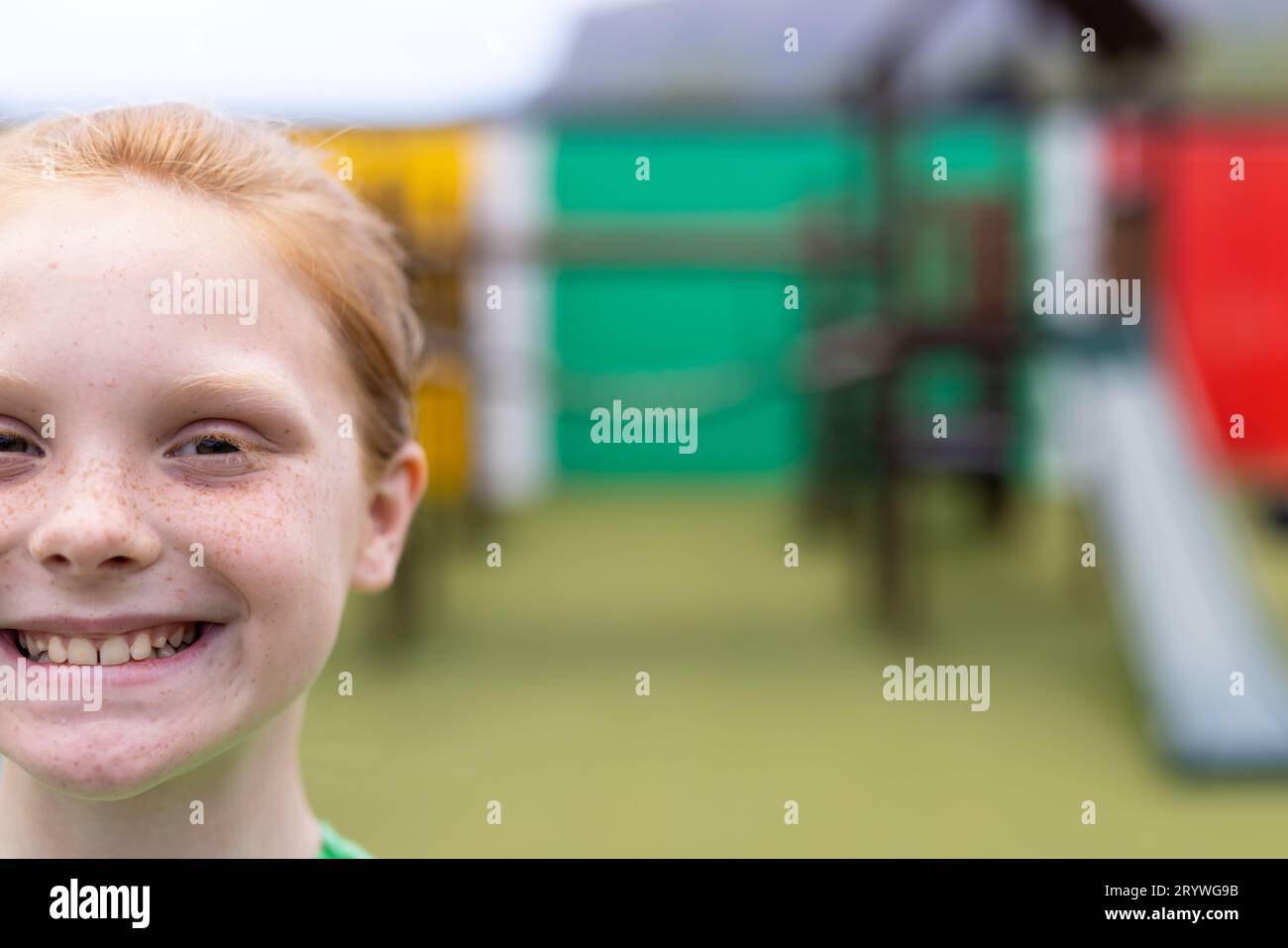 Half face portrait of smiling caucasian schoolgirl in schoolyard, with copy space Stock Photo