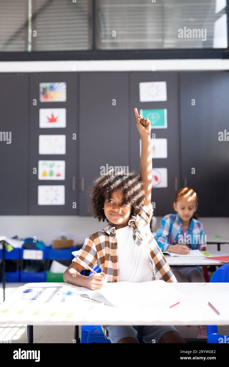 Vertical of smiling african american boy raising hand in elementary ...