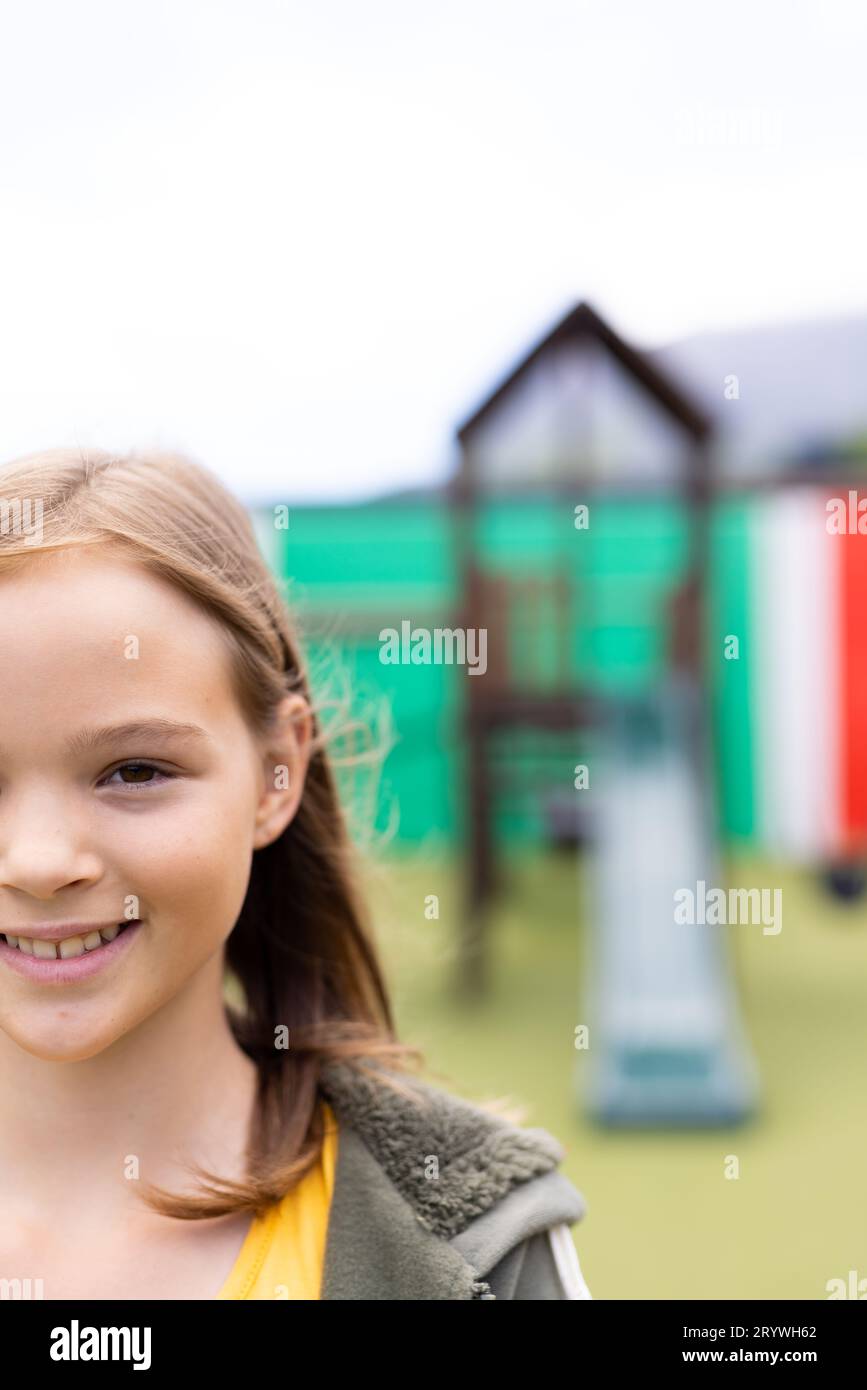 Vertical half face portrait of smiling caucasian schoolgirl in schoolyard, with copy space Stock Photo