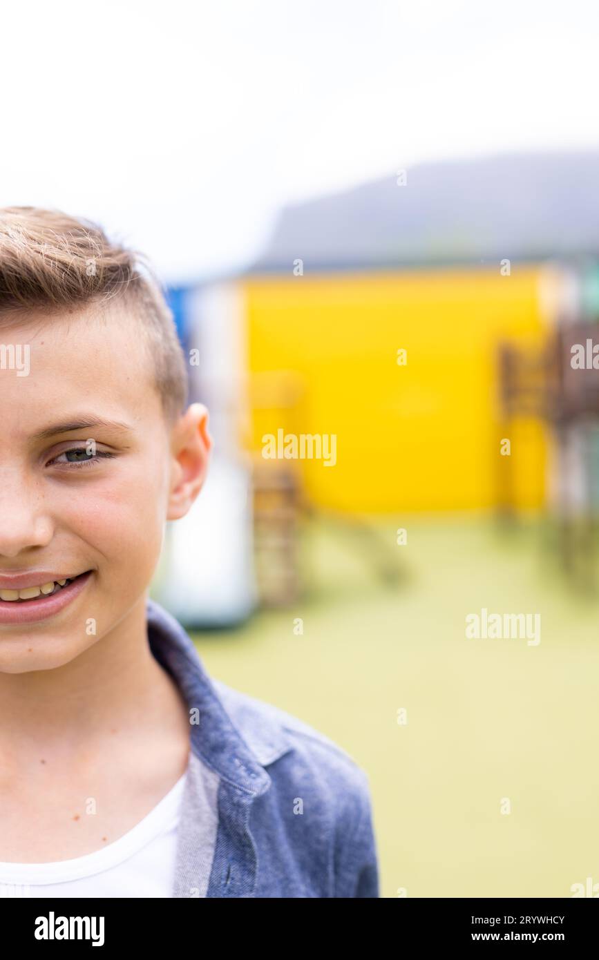 Vertical half face portrait of smiling caucasian schoolboy in schoolyard, with copy space Stock Photo