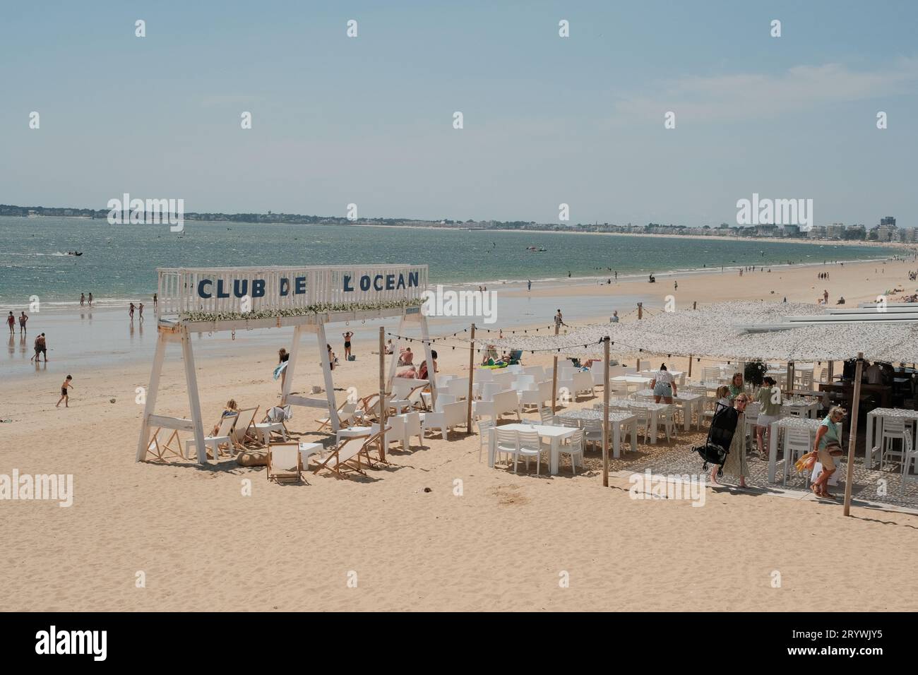 A group of people is seen enjoying a sunny day at the beach Stock Photo ...