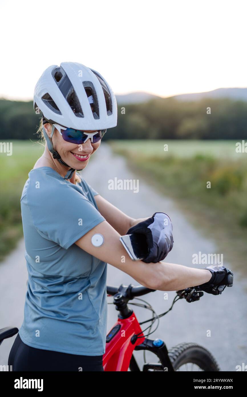 Diabetic cyclist with continuous glucose monitor checking on smartphone