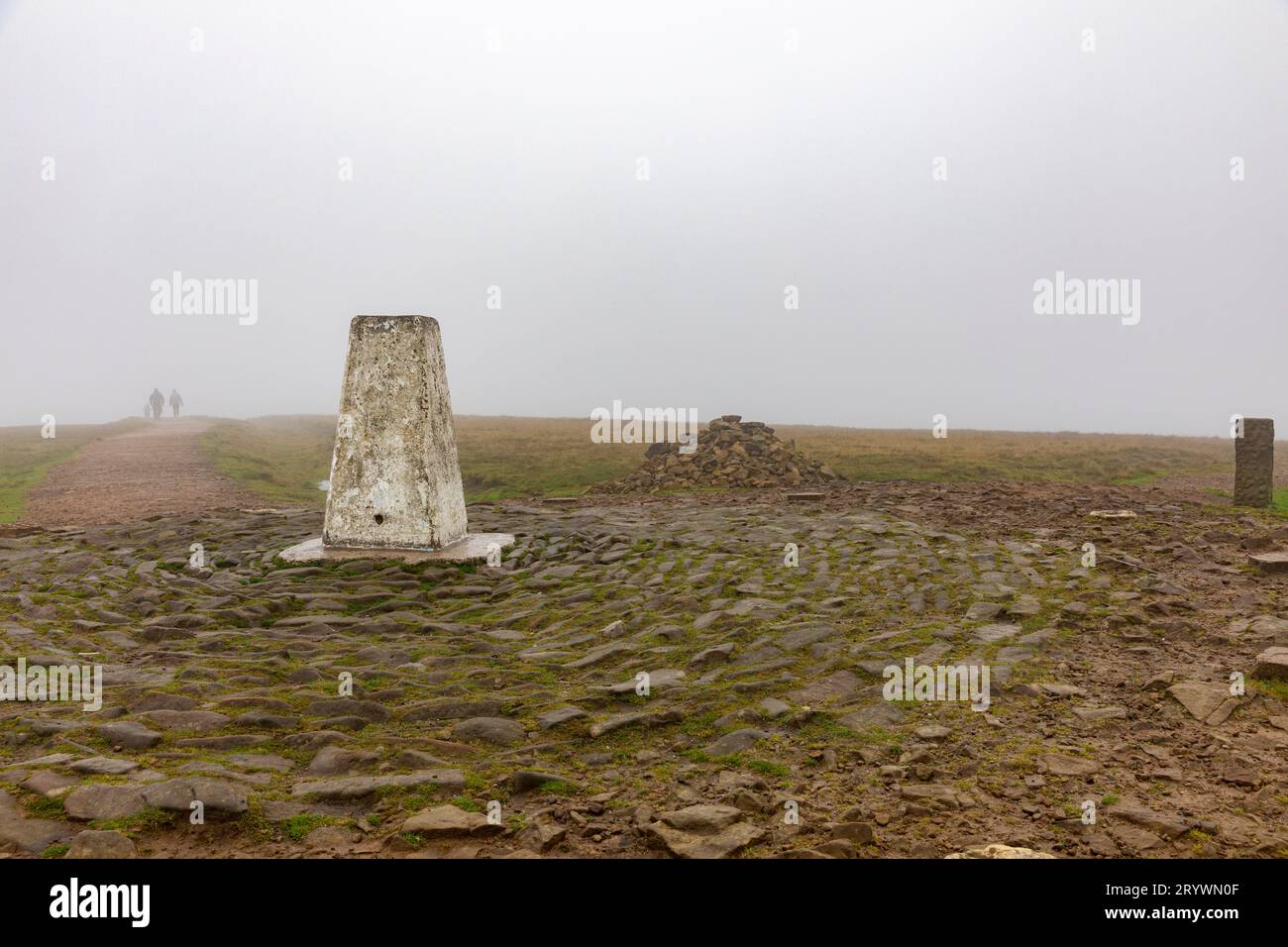 Summit of Pendle Hill Lancashire fog and mist as walkers walk away from Trig Point, Lancashire,England,UK Stock Photo
