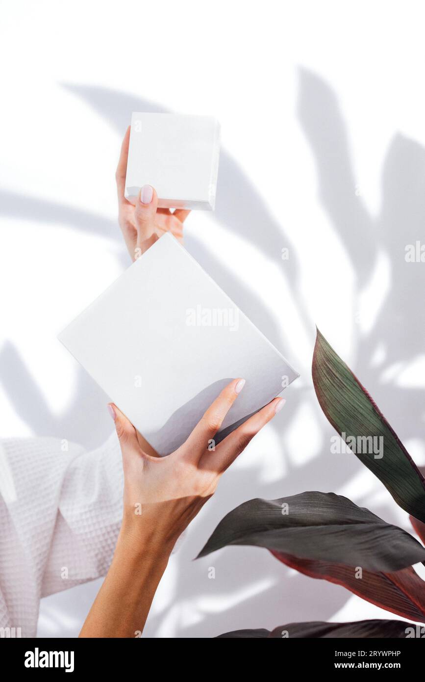 Woman in a white bathrobe takes care of her skin and moisturizes it her face with a serum Stock Photo