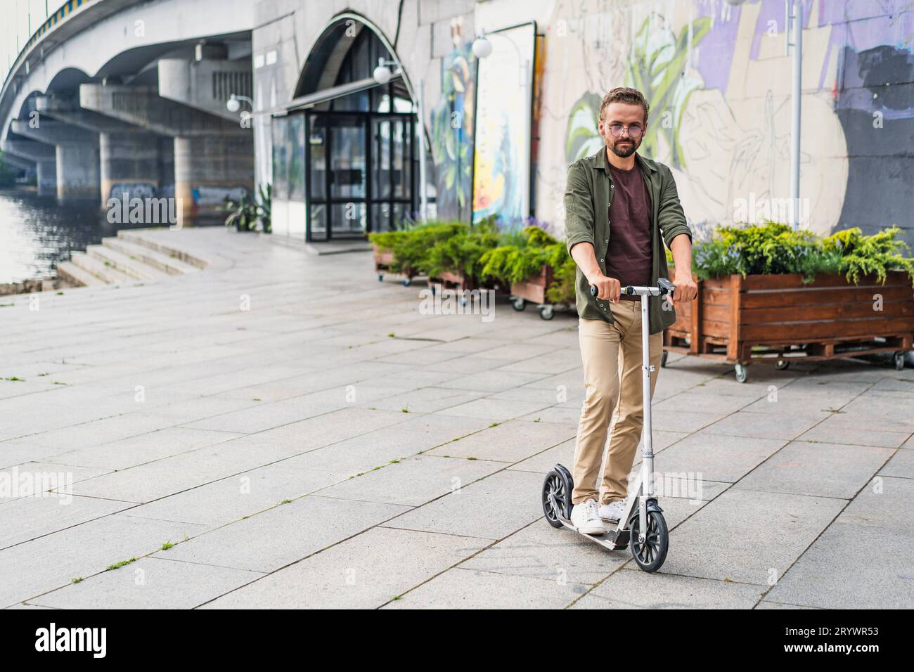 Man riding a scooter as he commutes home from work. The concept of a new city vehicle is embodied by this eco-friendly and effic Stock Photo