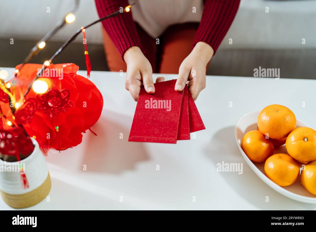 Asian Woman giving red envelope for Lunar New Year celebrations. Hand hold red packet Stock Photo